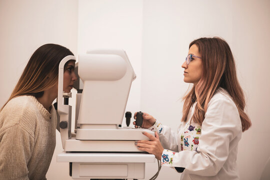 A beautiful young woman undergoes an objective graduation at an optician with an autorefractometer.