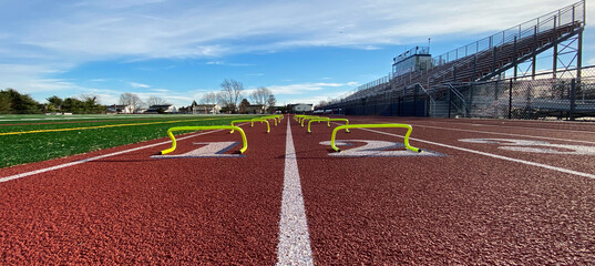 Looking down the track at yellow mini hurdles in two lanes