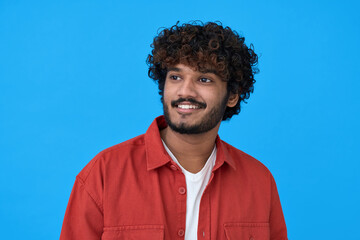 Happy smiling dreamy young indian man student looking aside thinking of new good future opportunities, dreaming, feeling positive standing isolated on blue background. Portrait