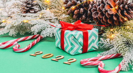 Gift box with red ribbons, fir branch with garland, heart shaped lollipops candy and wooden numbers