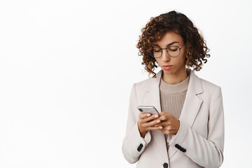 Attractive businesswoman in glasses using mobile phone, messaging, using social media app, reading...