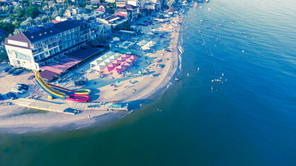 At dawn. Seashore, beach, inflatable slides and a vintage car with a surfboard on the trunk.