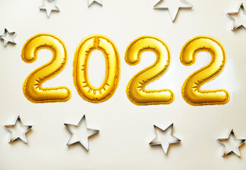 Balloons made of gold foil 2022 on a white background. Metallic shapes of stars.Christmas and New...