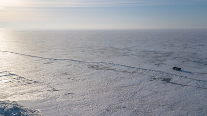 Lake Khanka in the Primorsky Territory in winter. View from above. Frozen coast of a large lake. Arctic landscape. A Russian minibus travels along a frozen lake.