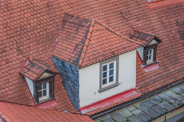 Three windows in a red-tiled roof of an old building in Europe