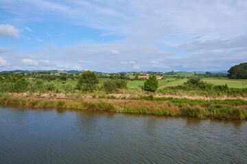 A river with vegetation along its banks under a cloudy sky