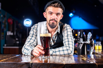 Young bartending pouring fresh alcoholic drink into the glasses while standing near the bar counter in bar