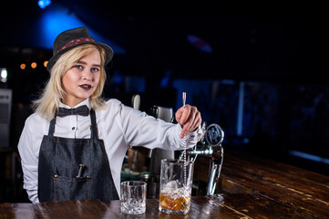 Charismatic girl bartender formulates a cocktail at bar