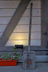 An old wooden shovel stands against a wall of wooden planks. An old-fashioned wood tool. Place for your text.