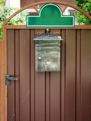 Patina mailbox hanging on a brown iron door