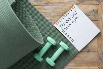 Notepad on the wooden background with the inscription - To do list - Join gym.
