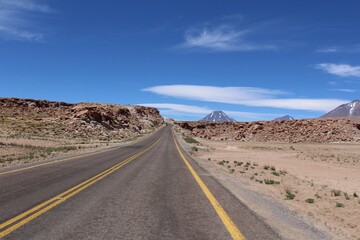 Fototapeta na wymiar Road (Route 23) on the Atacama Desert with volcanos on the background, Chile, South America.