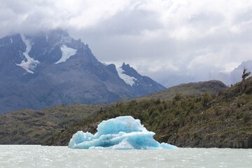 Blue iceberg floating on Grey Lake on a cloudy day at Torres del Paine National Park, Patagonia, Chile.