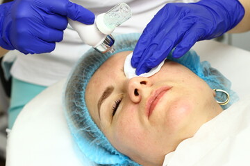 Beauty salon. A cosmetologist in medical gloves and protective mask doing a hydra peeling procedure...