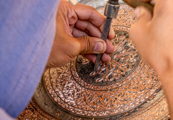 Uzbekistan, City of Bukhara, an artisan is working on a brass plate.