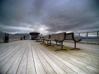 Beautiful shot of benches on the pier on a cloudy day