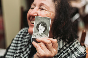 Elderly woman holding a photo of her young self. Passing of time concept