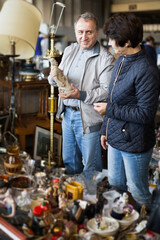 Fototapeta na wymiar Loving senior couple choosing vintage goods at flea market