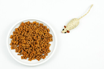 Cat food. Dry food in cat bowl and cat toy on white background Top view