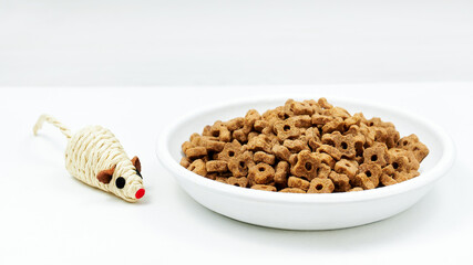 Cat food. Cat dry food in bowl with toy mouse on white background