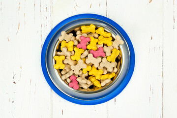 Dog food. Bowl with kibble dry food on white wooden floor