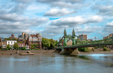 Riverside houses in Hammersmith, West London, England, with the historic Hammersmith Bridge that crosses the River Thames on the right. Photo taken from the south bank, from Barnes.