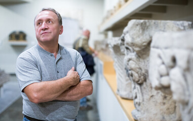 Obraz premium portrait of adult man is visiting museum and looking at the exposition indoor.