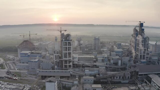 Aerial photo panorama of a drone copter of an industrial factory factory in dense waves of fog at sunrise. Such objects are necessary for the economy, but harmful for ecology.
