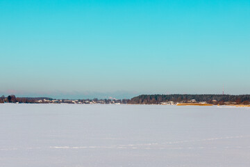 Winter landscape with ice covered lake or river with shores and clear sky