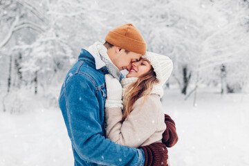 Valentine's day. Young loving couple walking in winter park. Man and woman hugging enjoying snowy landscape outdoors