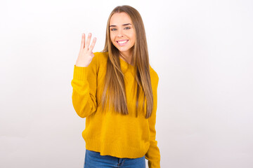 Young caucasian girl wearing yellow sweater over white background smiling and looking friendly,...