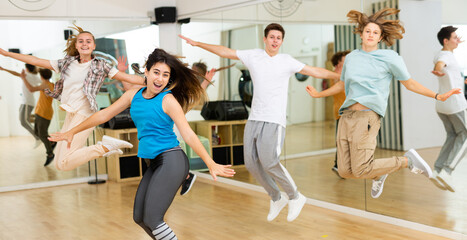 Fototapeta na wymiar Group of happy teens jumping during exercising in choreography class