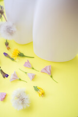 Close-up white bottle with wild flowers on the yellow table