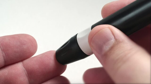 Test of blood sugar level with glucometer for diabetes, finger with blood drop and glucose monitor device, macro shot.