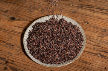 Place the black rice in the plate or bowl on the wood grain table