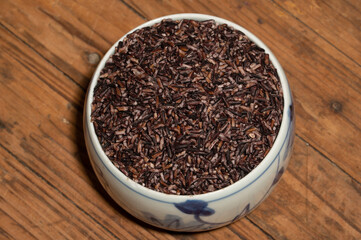 Place the black rice in the plate or bowl on the wood grain table