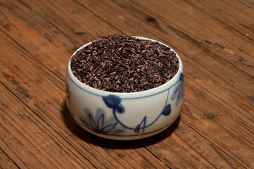 Fototapeta na wymiar Place the black rice in the plate or bowl on the wood grain table
