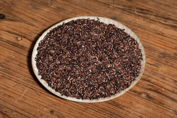 Place the black rice in the plate or bowl on the wood grain table