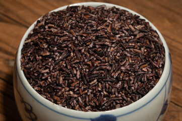 Place the black rice in the plate or bowl on the wood grain table