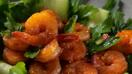 Fresh salad with grilled prawns, cucumbers and arugula, served on a plate, close-up