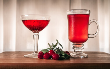 Flavored red fruit cider accompanied by cherries, on a wooden surface