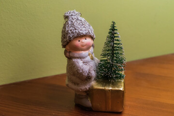 Kid in white with christmas three and gift