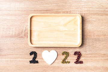 2022 new year made from bean seed (black soybean, mung bean and azuki bean) with white heart shape and wooden plate on wooden background