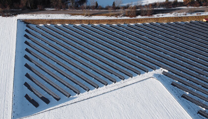 Luftaufnahme mit einer Drohne von einem großen Solarpark in einer Wiese im Winter