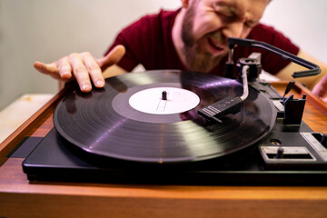 Funny closeup shot, hipster bearded man scratching vinyl record on vintage turntable 