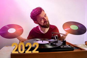 Hipster DJ with two vinyl records in his hands playing music on turntable , golden 2022 numbers 
