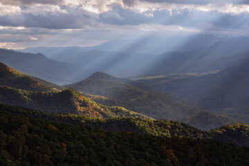 Crepuscular light rays shining across the North Fork Valley in West Virginia, illuminating some of the early Autumn color down below. - obrazy, fototapety, plakaty