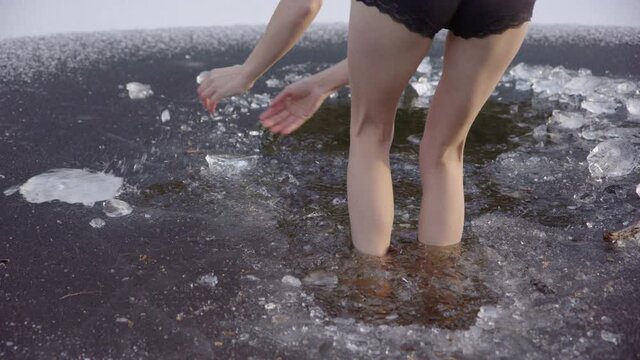 SLOW MOTION - Beautiful legs of a young woman walking into icy water, jumps out