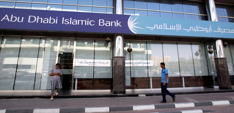 Men walk past a branch of Abu Dhabi Islamic Bank along Khalid Bin Al-Waleed Road in Dubai