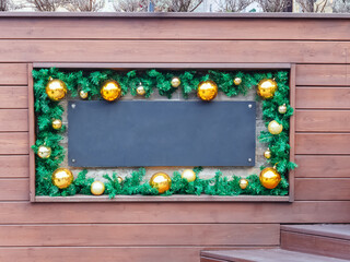 Blank mocup black plaque in a frame with New Year's decor in the form of fir branches and golden...